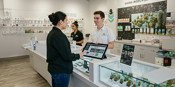 2 a tablet displaying products, while two staff members assist